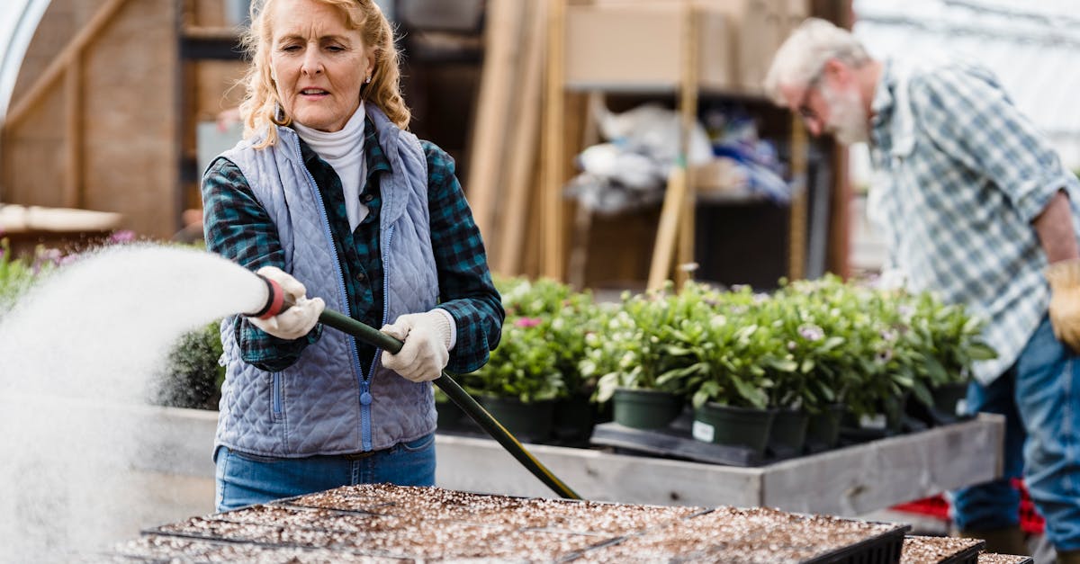senior woman watering plants in a greenhouse focusing on growth