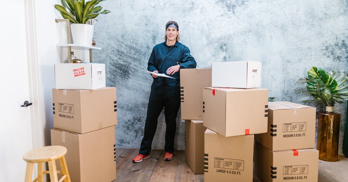 smiling mover in coveralls standing with parcels clipboard in hand indoors
