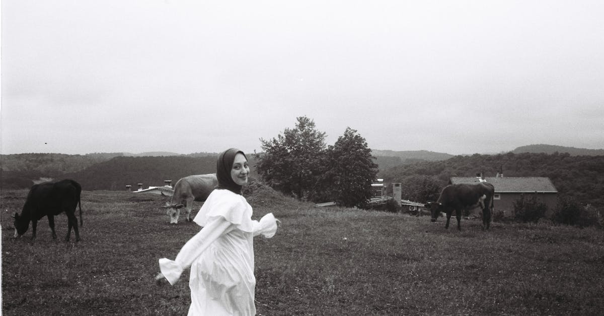 smiling woman in hijab walking in rural countryside with cows