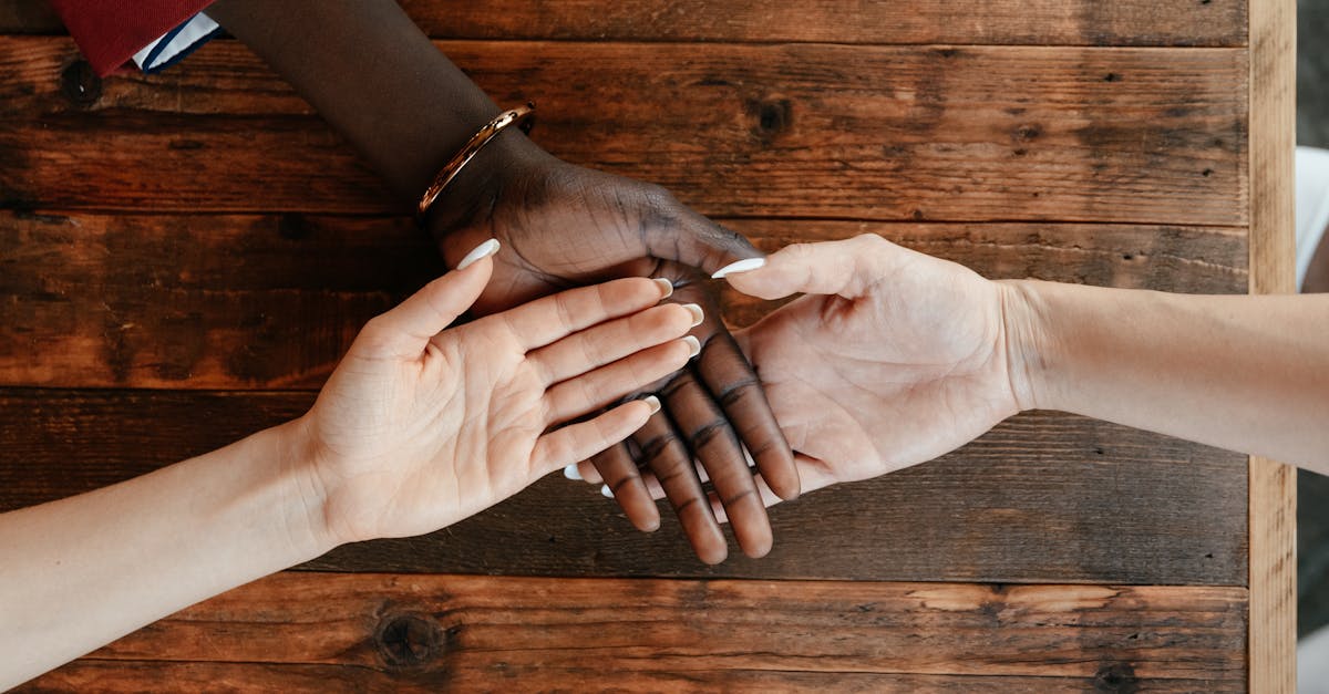 top view of diverse hands joining together in harmony on a wooden table symbolizing unity