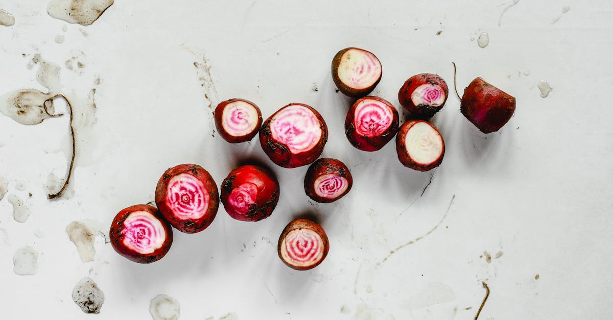 top view of fresh chioggia beets cut in halves showcasing vibrant pink and white stripes on a white 2