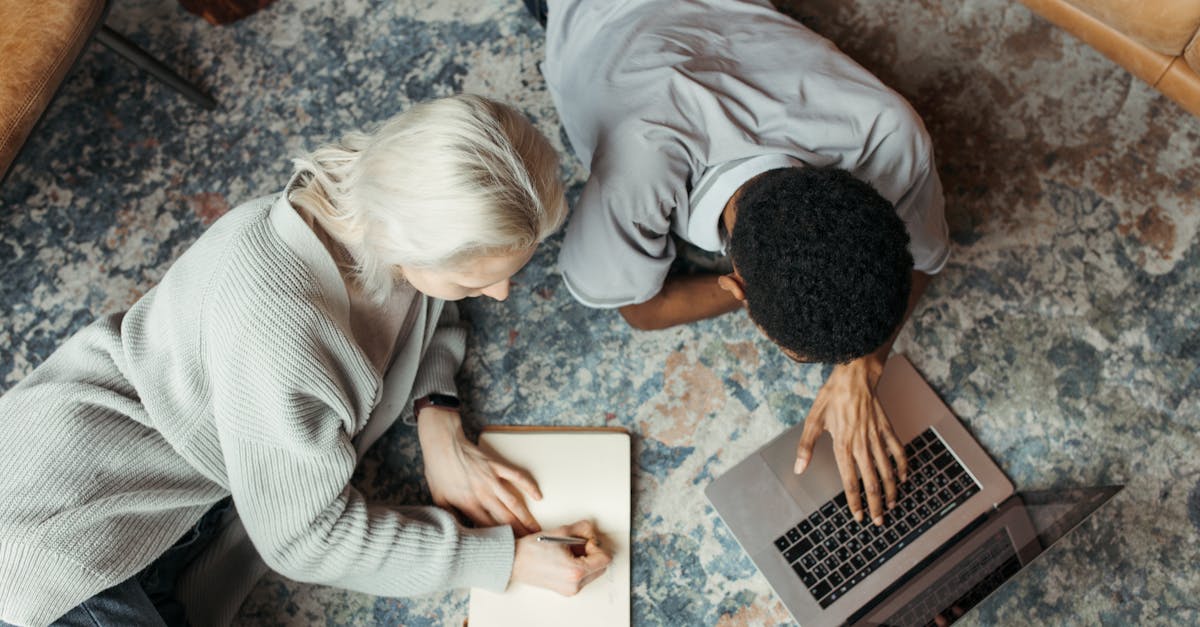 two adults working together on the floor with a laptop and notebook 1