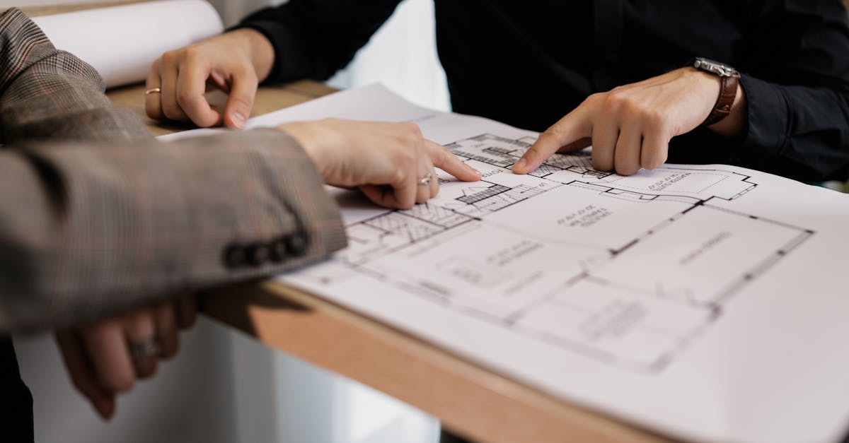two architects reviewing and pointing at a detailed floor plan on paper in an office setting