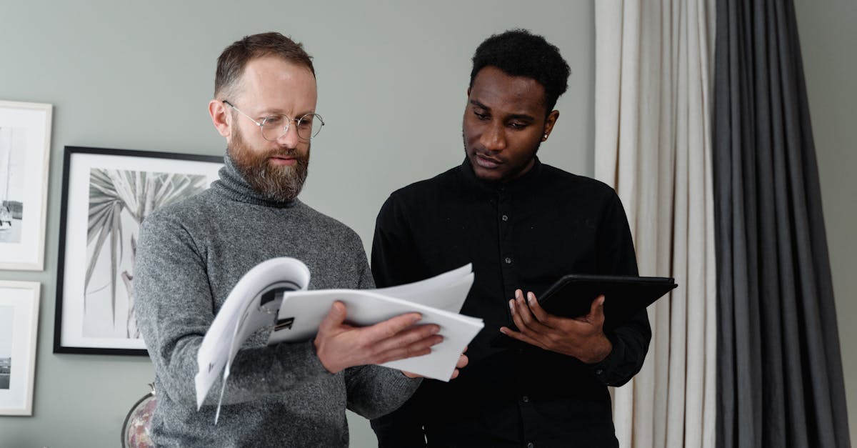 two businessmen analyzing documents and using a tablet in a modern office setting