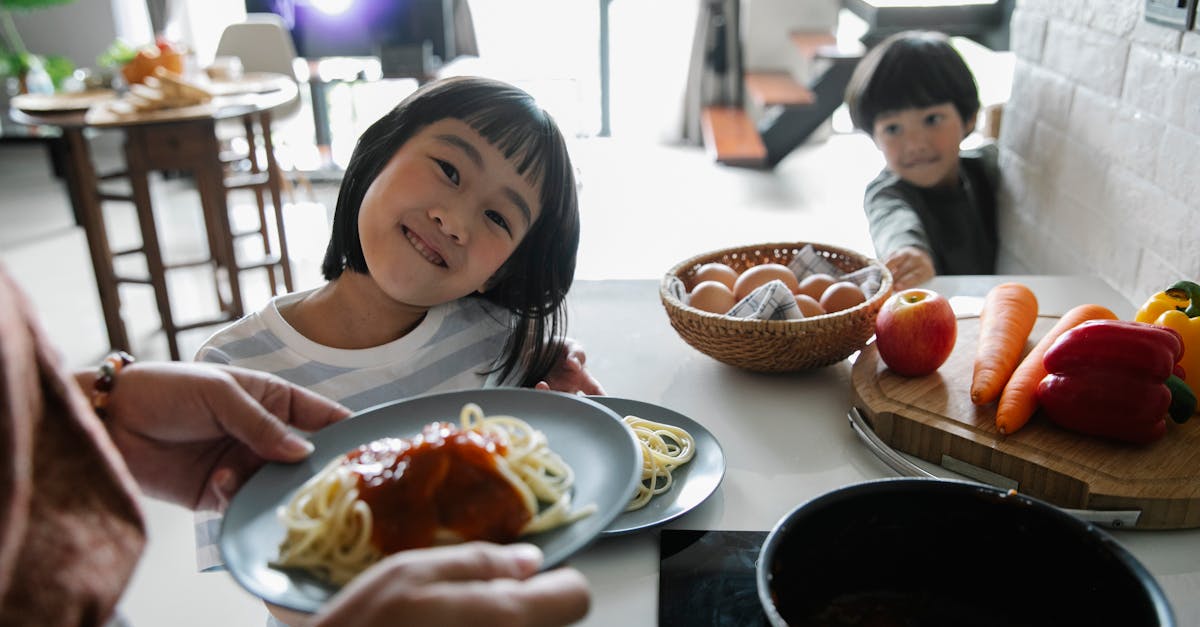 two cheerful children in a modern kitchen enjoying a delicious plate of homemade spaghetti with toma