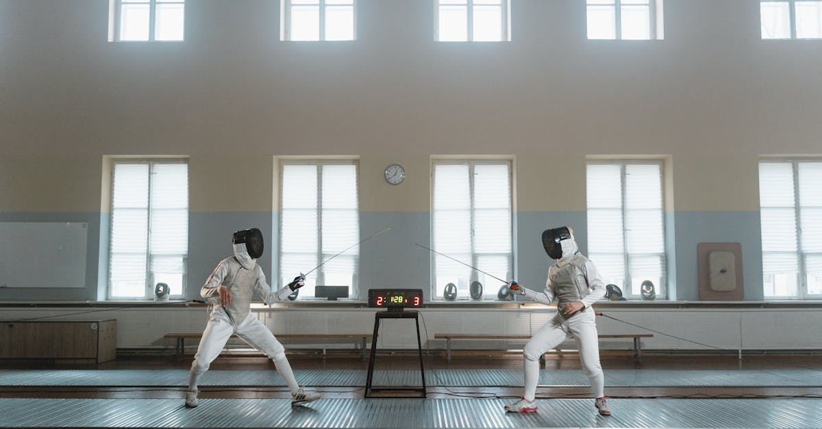 two fencers in action during a practice match indoors with an electronic scoreboard