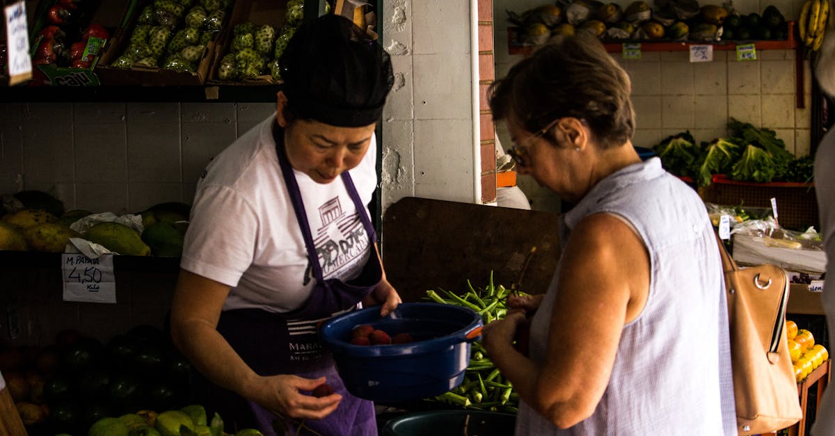 two women interacting over fresh produce in an outdoor market setting