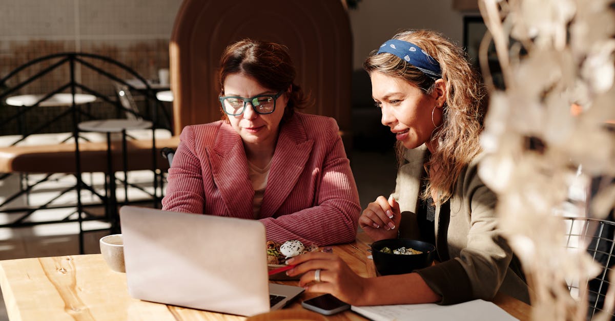 two women working together on a laptop in a cozy cafe setting 2