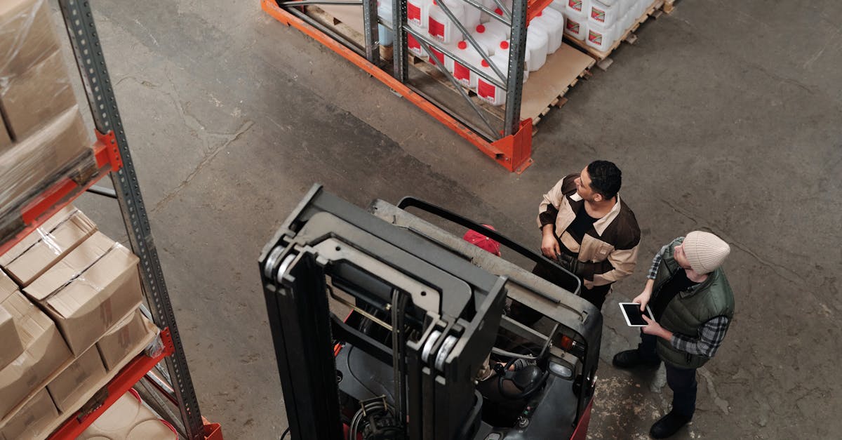 two workers in a warehouse discussing logistics near a forklift captured from above