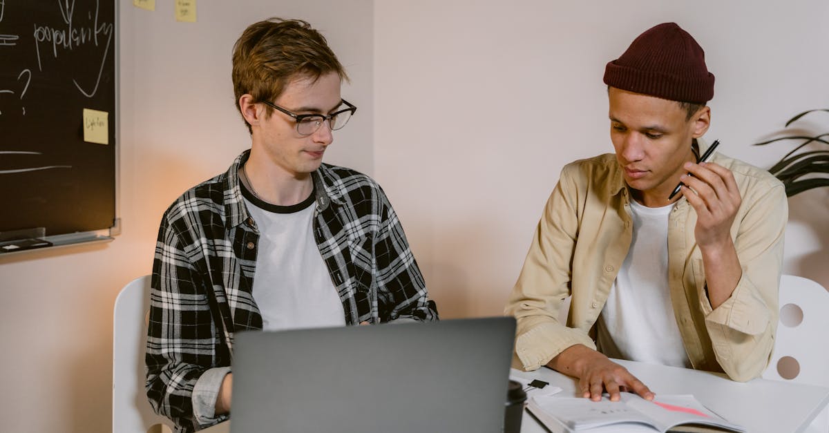 two young colleagues working together at a laptop in a modern office setting