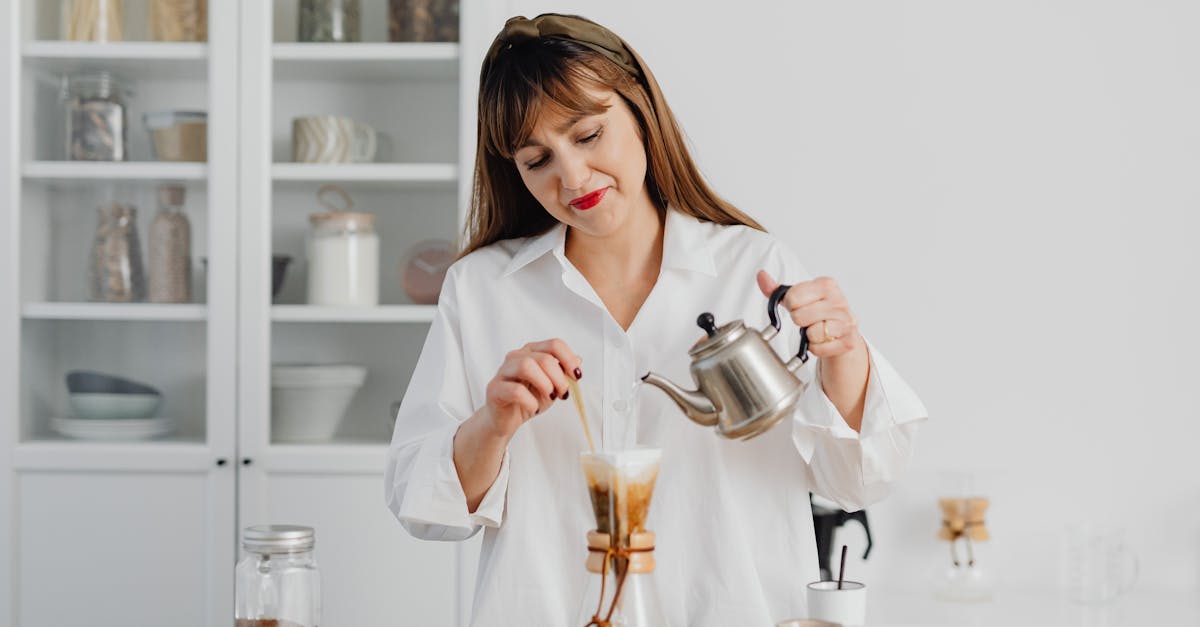 woman in white shirt making pour over coffee in a modern kitchen setting