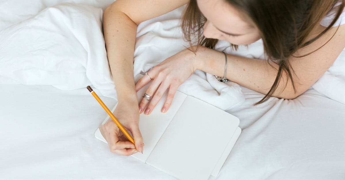 woman relaxing on a bed while writing in a journal with a pencil 5