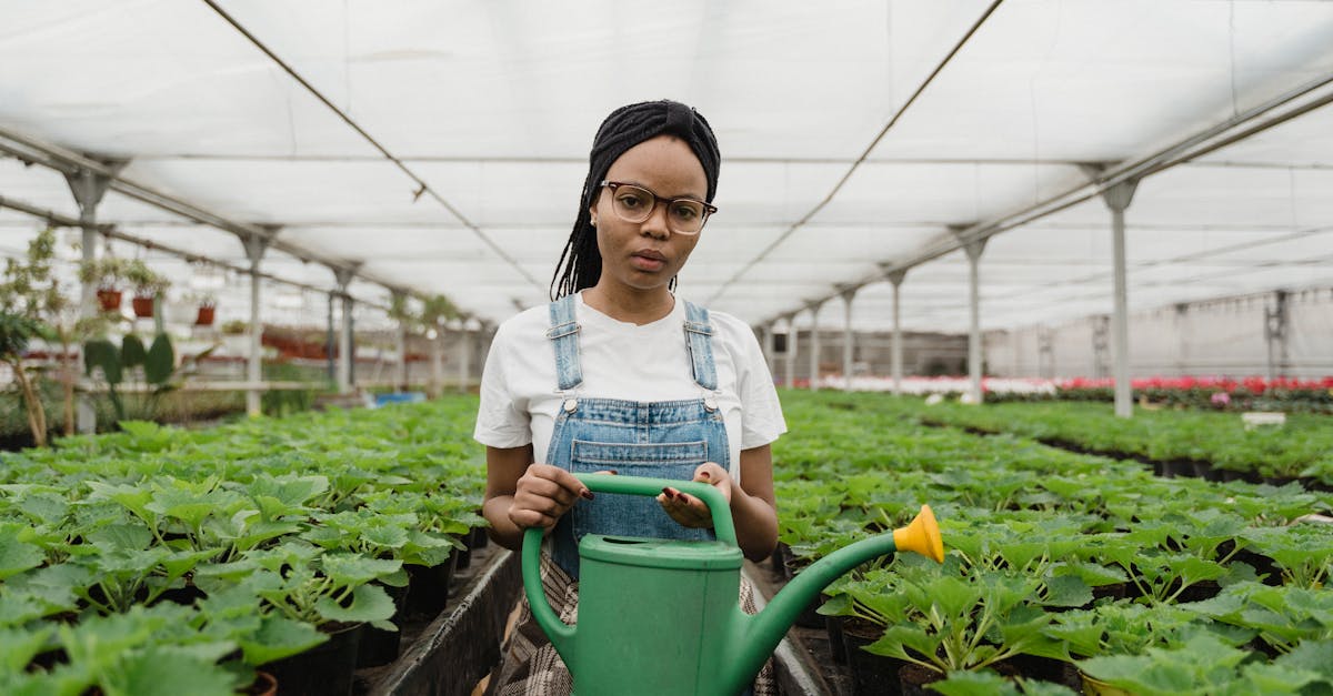 woman tending plants in a greenhouse holding a watering can showcasing sustainable agriculture