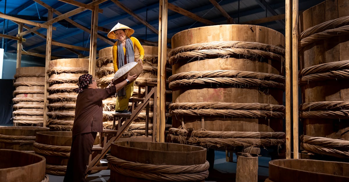 women making fish sauce using traditional methods with large wooden barrels