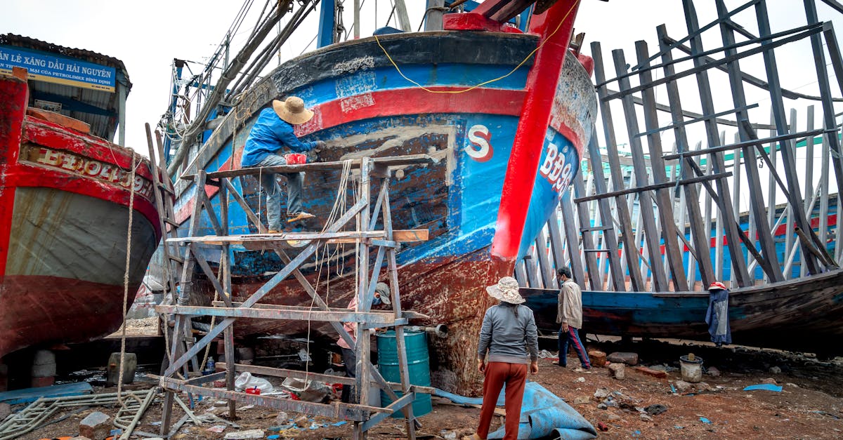 workers actively repair colorful wooden fishing boats on a dockside showcasing craftsmanship and te