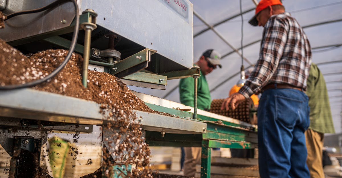 workers operating machinery in a greenhouse for soil production