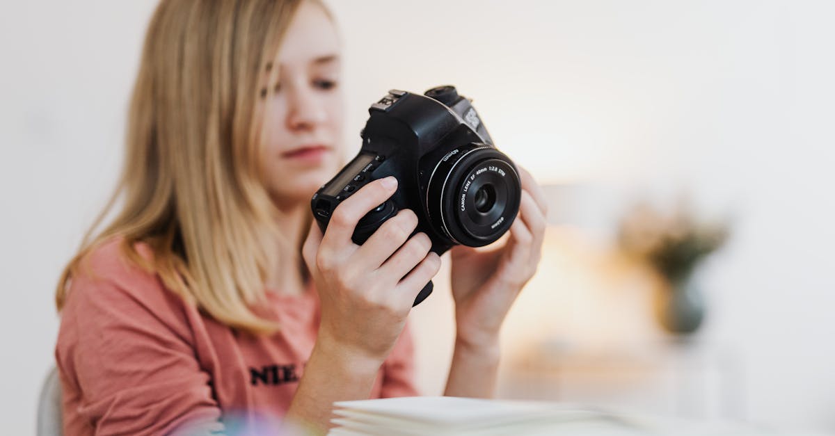 young woman examining a dslr camera indoors with a blurred background