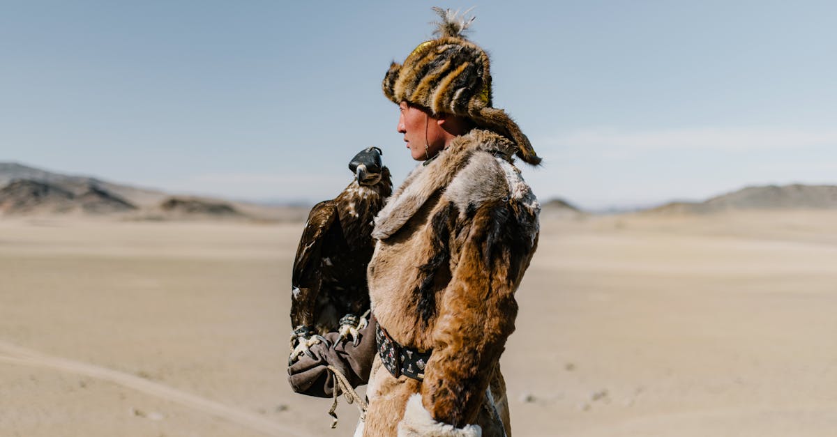 a mongolian hunter with an eagle in the desert showcasing traditional falconry skills