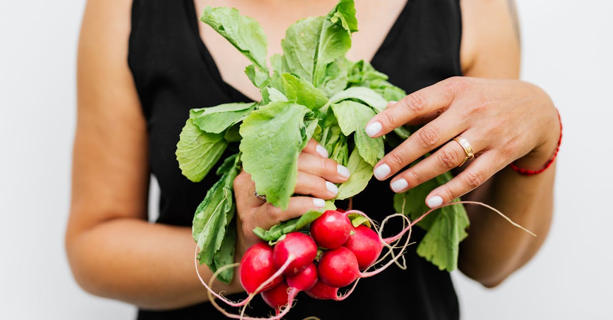 a person holding fresh radishes with vibrant green leaves against a white background