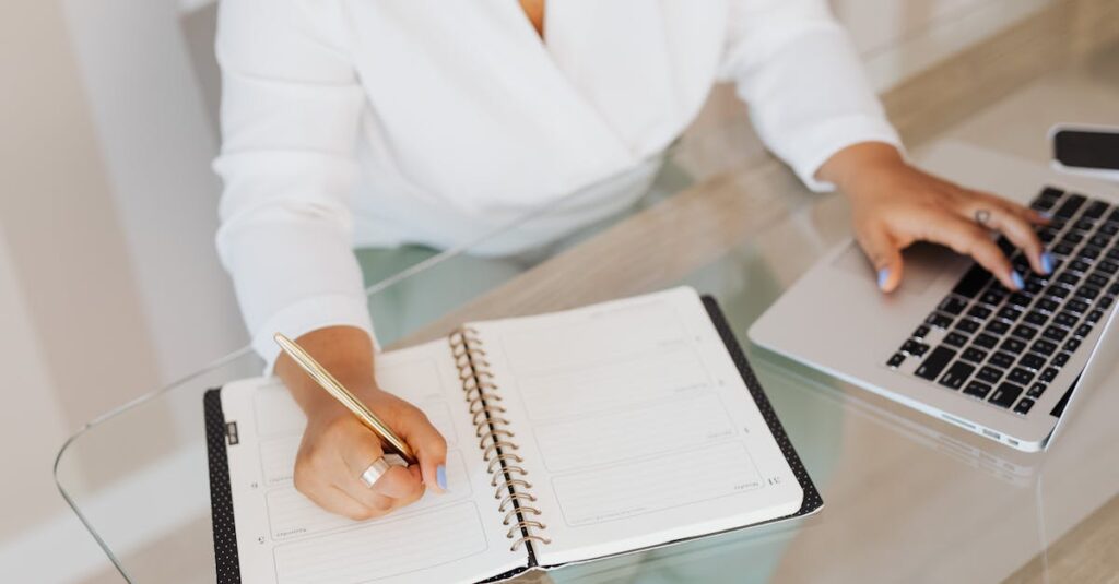 a person planning and typing on a laptop at a glass desk