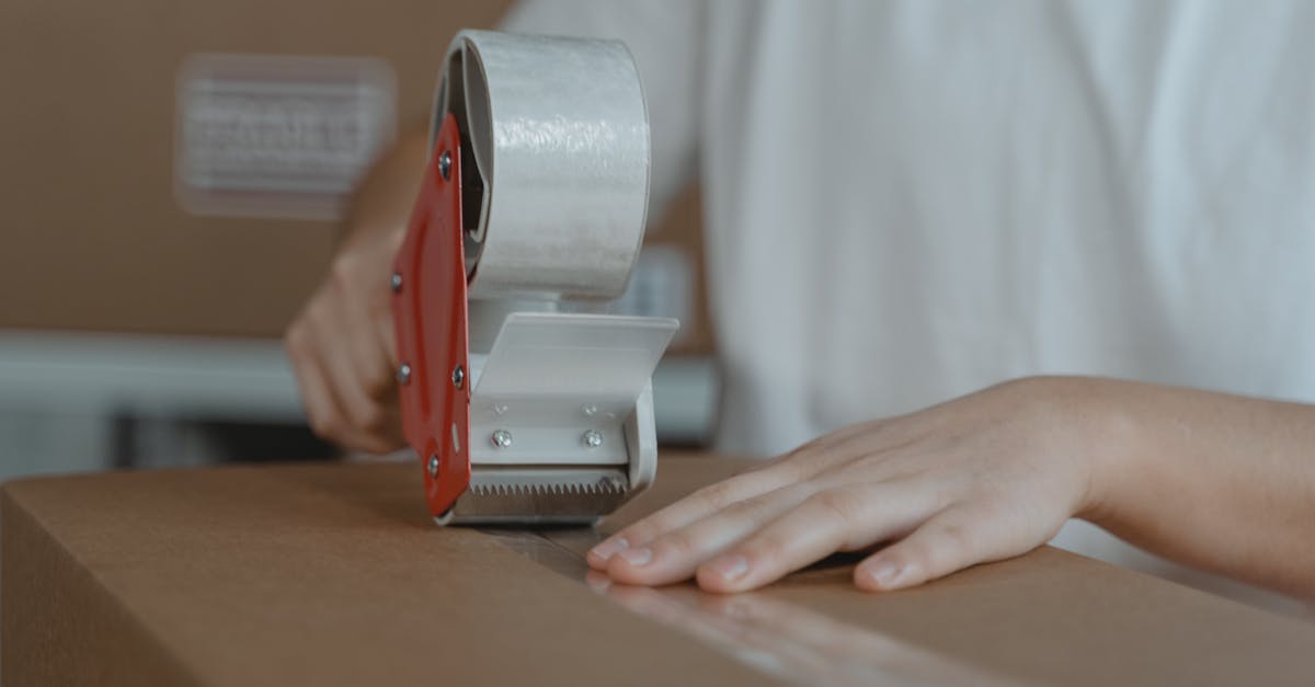a person sealing a cardboard box with tape emphasizing packaging and shipping processes