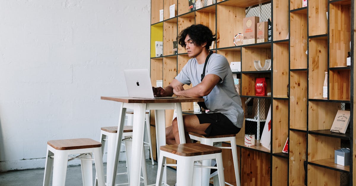 a young man sits in a loft cafe working on a laptop surrounded by wooden decor and shelving 1