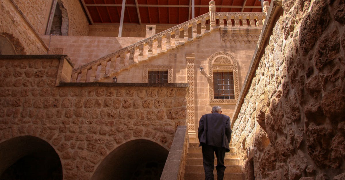 an elderly man climbs steps in a sunlit historic stone courtyard capturing timeless architecture