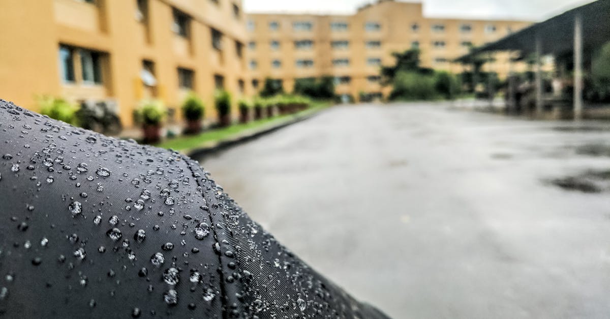 close up of raindrops on a surface with urban buildings in the background capturing a rainy day atm