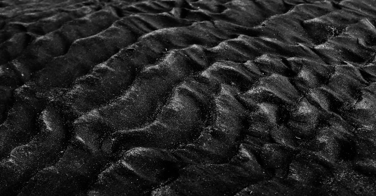 close up of textured black sand dunes in monochrome showcasing natural patterns and