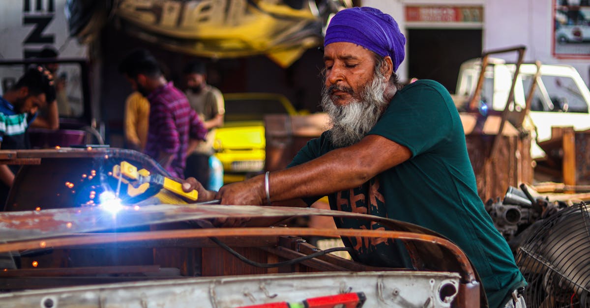 man welding a car s metal frame in a busy workshop setting