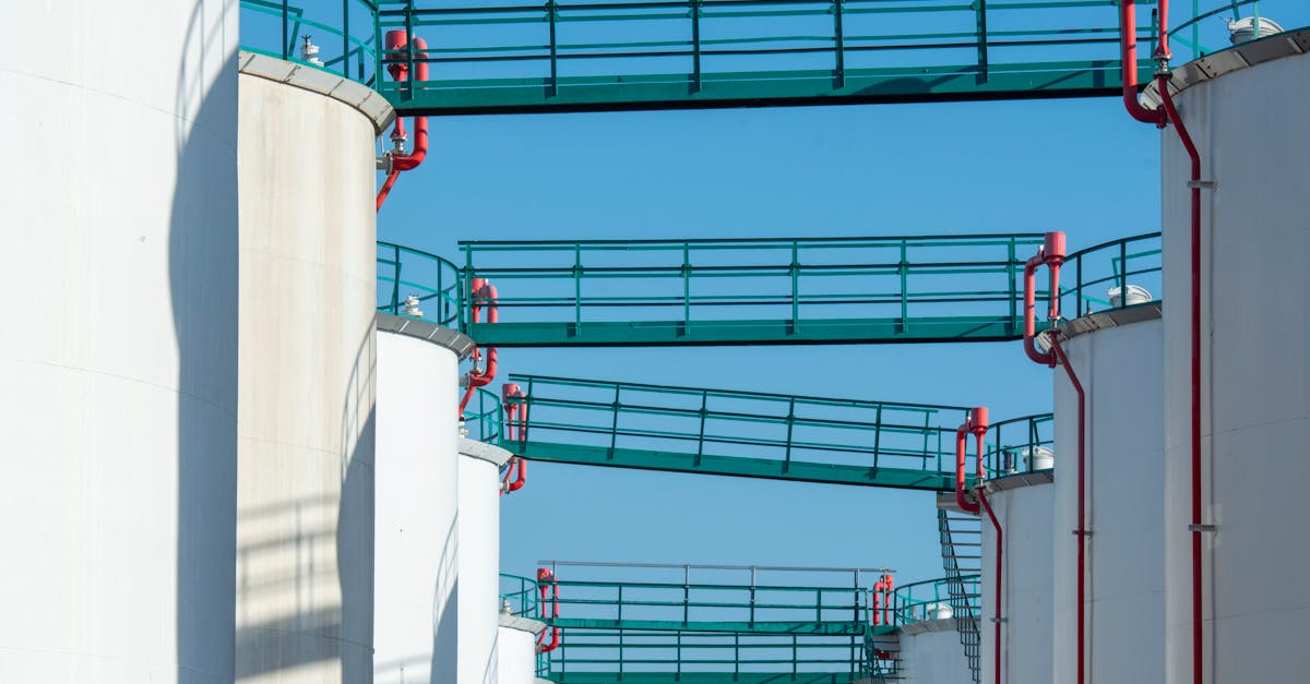 modern industrial storage tanks with walkways against a clear blue sky
