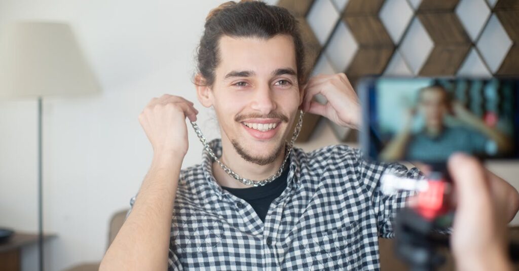 smiling man vlogging indoors with a smartphone camera creating online content