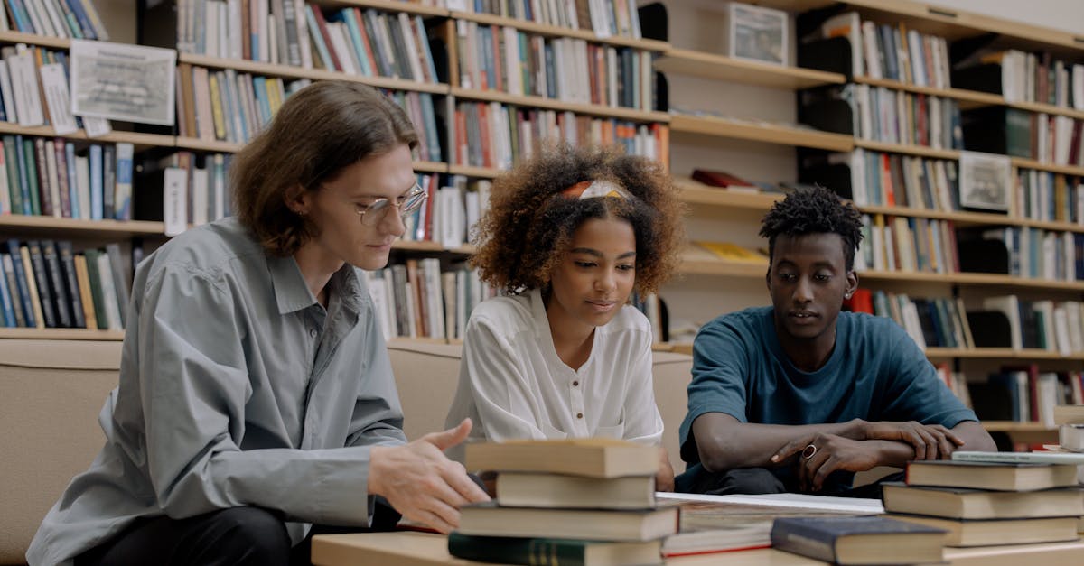 three students studying together in a library surrounded by books and learning materials