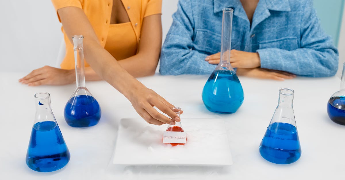 two women in a laboratory setting conducting an experiment using erlenmeyer flasks containing blue