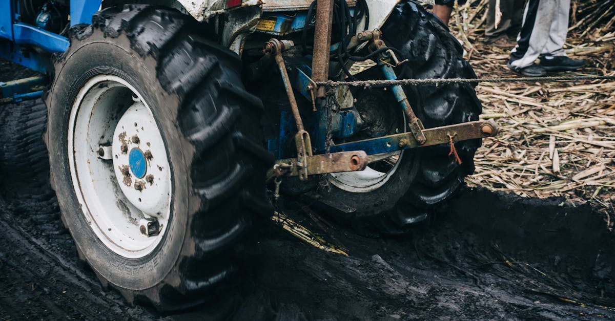a blue tractor working the soil in a farm field during the day