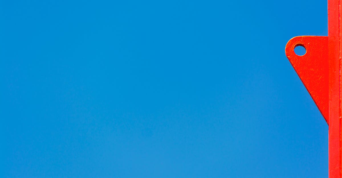 a bright red metal post against a clear blue sky creating a vibrant minimalist composition