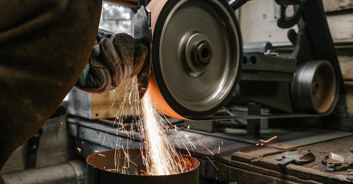 a close up of a metalworker grinding a blade creating sparks in a workshop setting