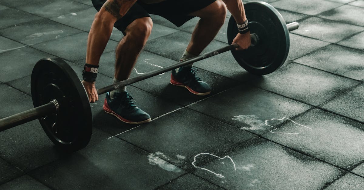 a muscular man in a gym preparing to lift a heavy barbell showcasing strength and fitness