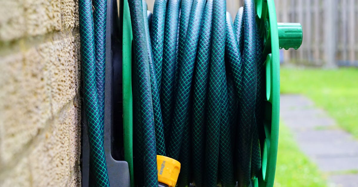 a neatly coiled garden hose on a wall mounted reel against a brick wall 6
