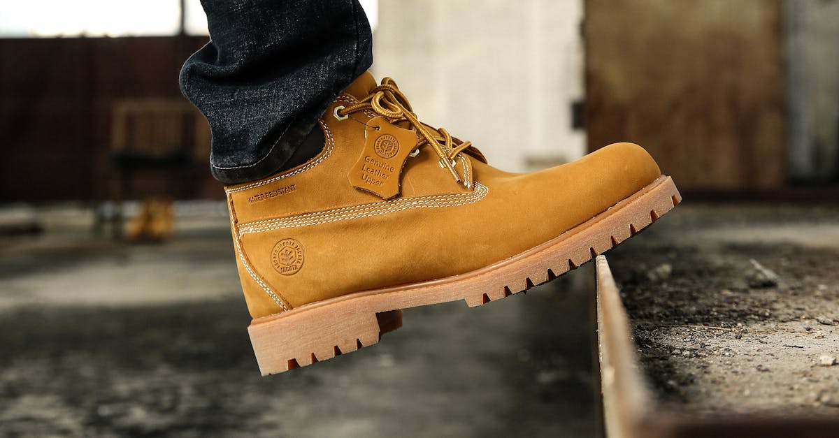 a rugged brown hiking boot steps onto a metal ledge in an industrial environment