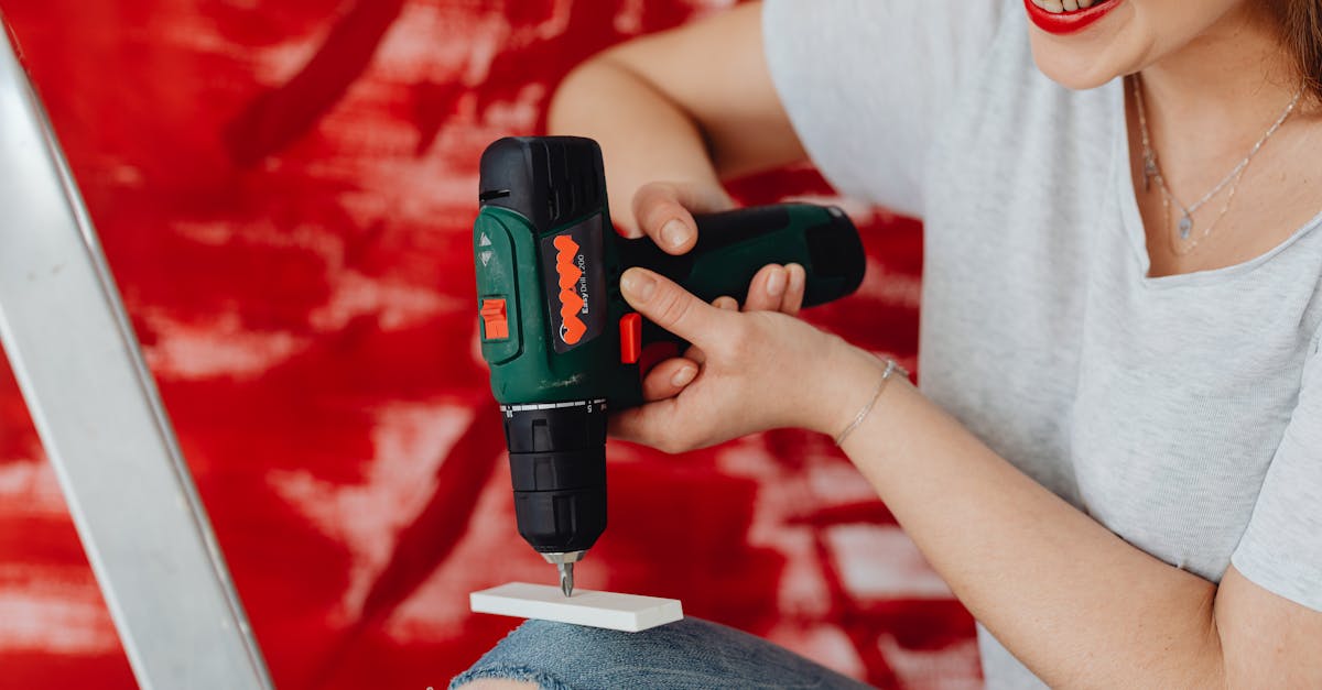 a smiling woman using a cordless drill engaged in a home renovation project with a red background