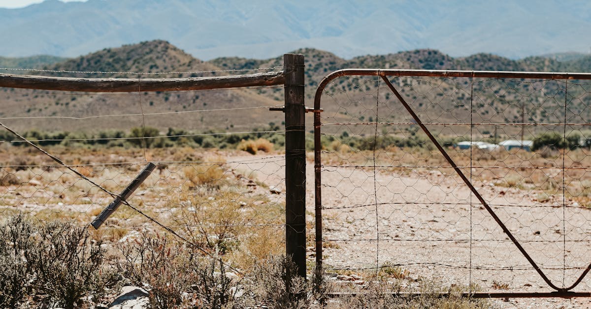 a tranquil desert landscape bordered by a rustic wire fence against a mountainous backdrop