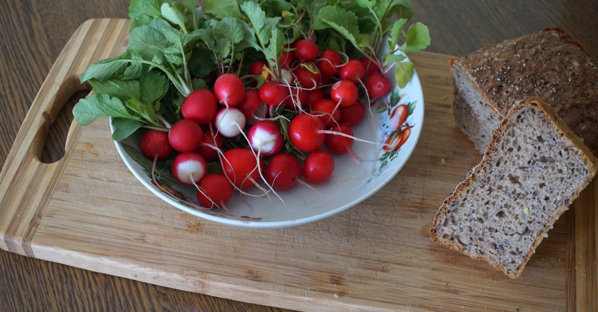 a vibrant display of radishes with leafy greens and whole grain bread on a wooden cutting board