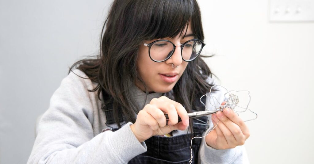 adult woman carefully shaping wire with pliers focused and creative indoors