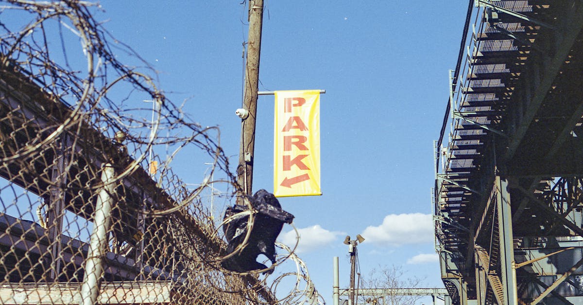 an industrial urban setting featuring barbed wire fences metal structures and a clear blue sky