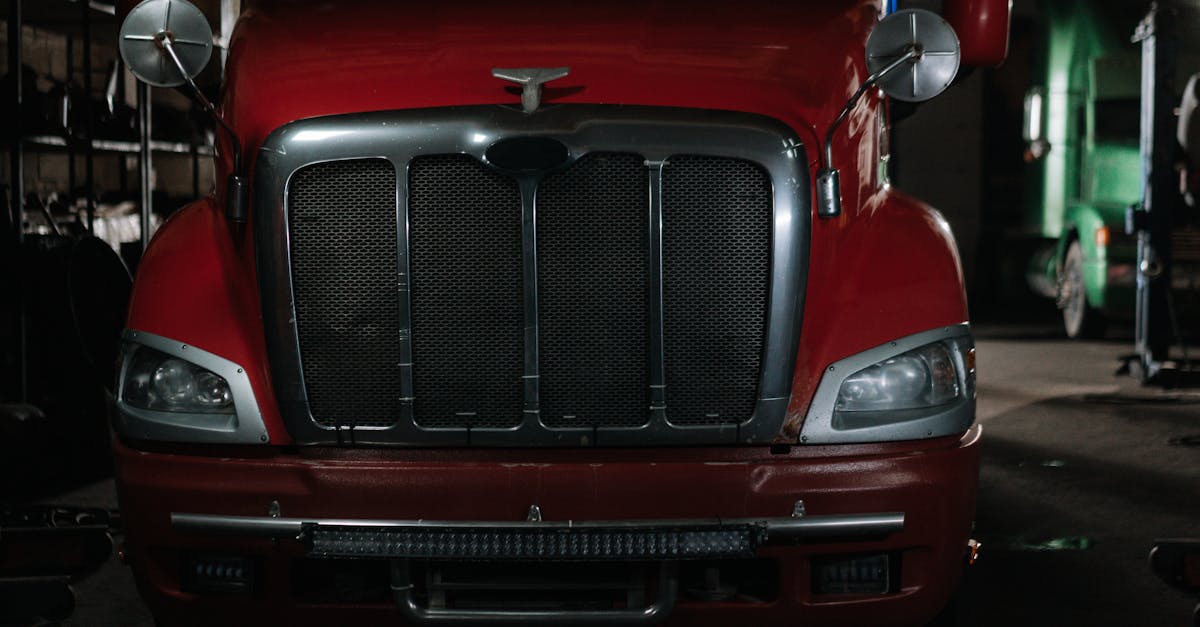 close up of a classic red semi truck in a dimly lit garage with chrome details