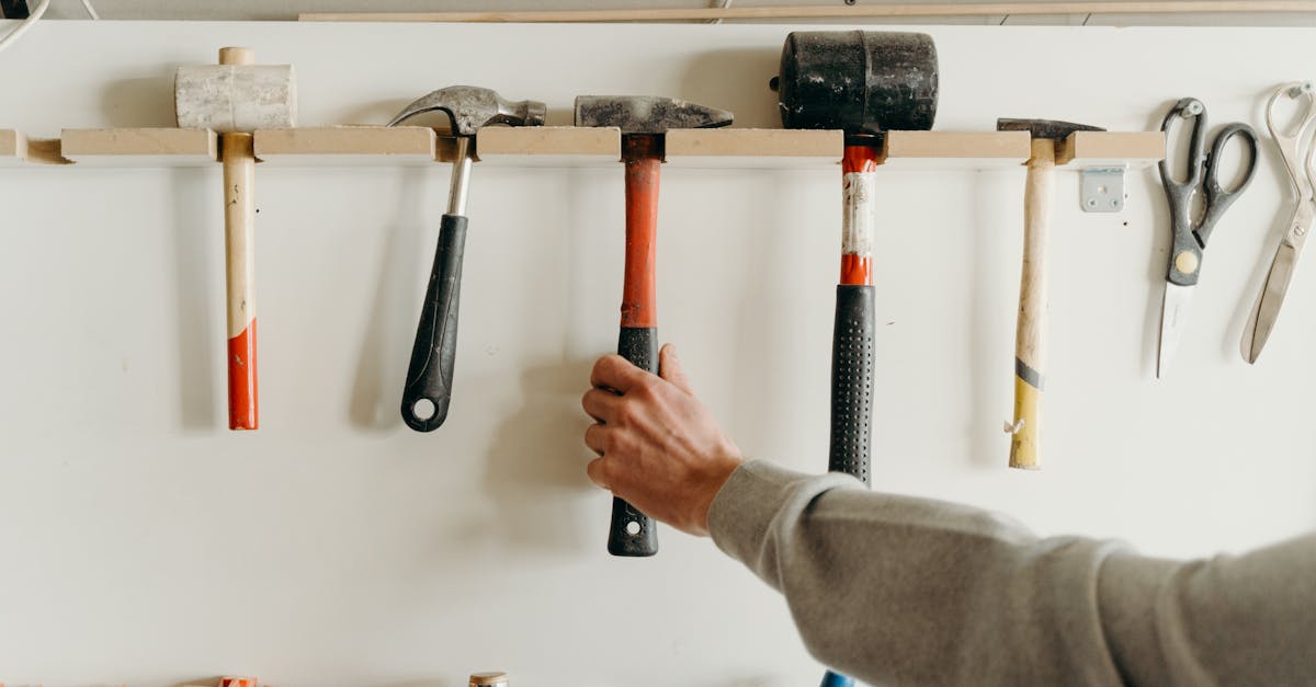 close up of a hand reaching for a hammer in a workshop with various tools