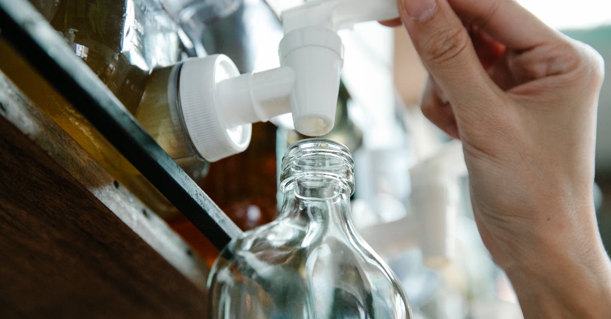 close up of a hand refilling a glass bottle from a liquid dispenser with a pump in an eco friendly s