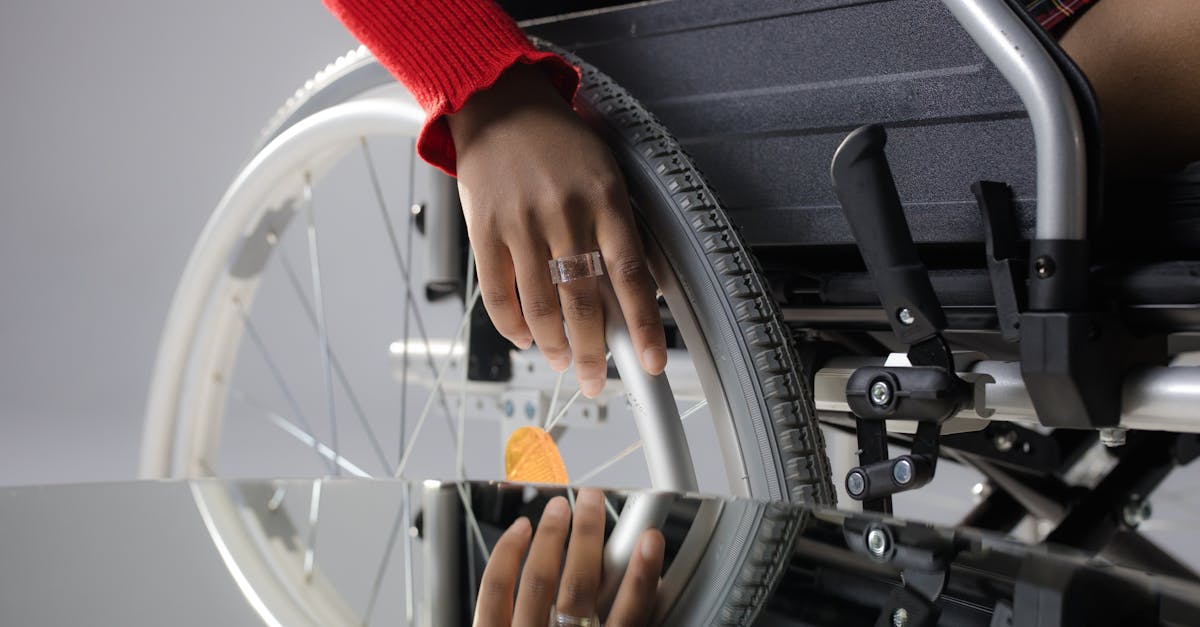 close up of a person s hand on a wheelchair wheel reflected in glass highlighting mobility and dis