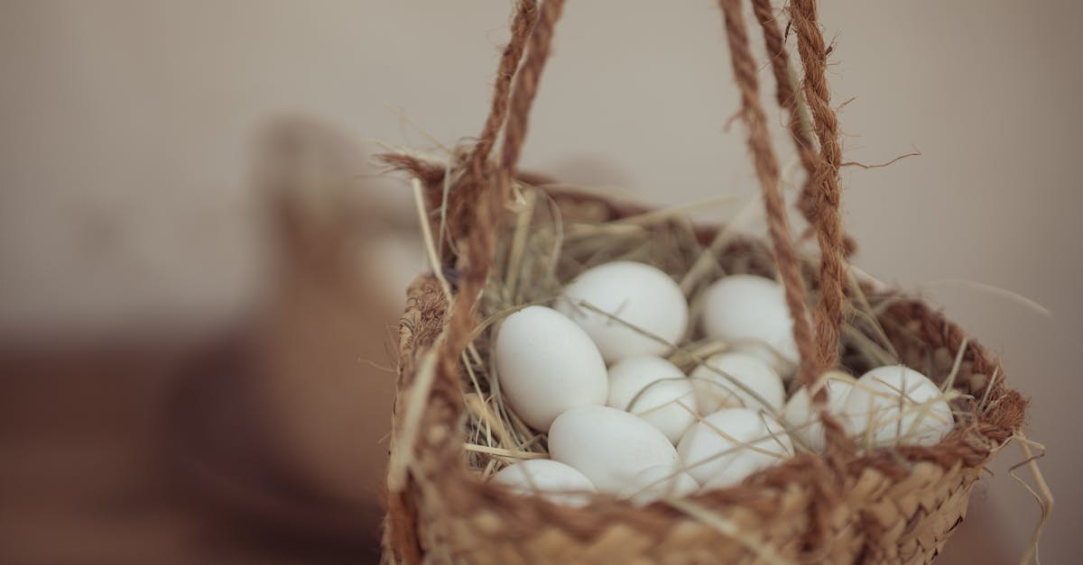 close up of a rustic woven basket filled with white eggs on a wooden surface